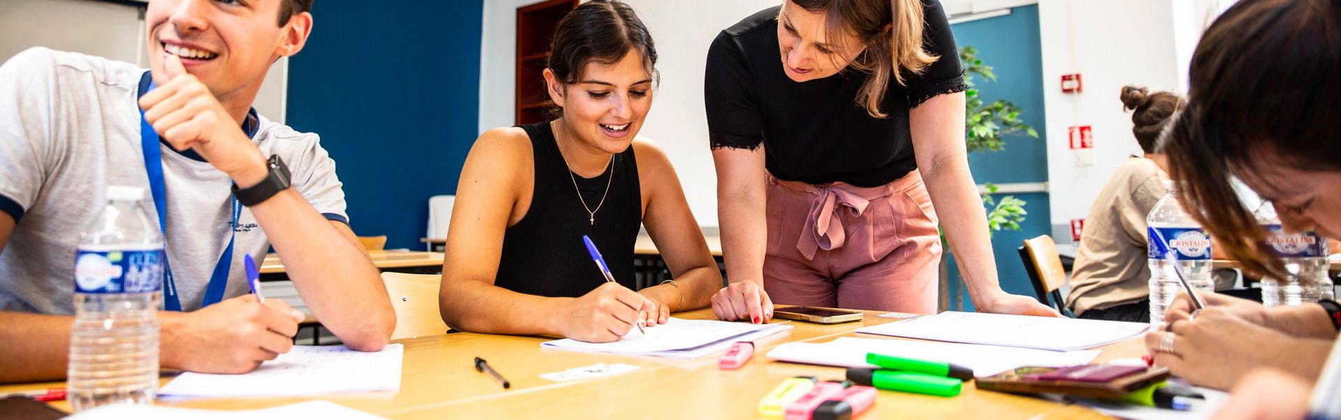 une professeure aide une étudiante à corriger un devoir